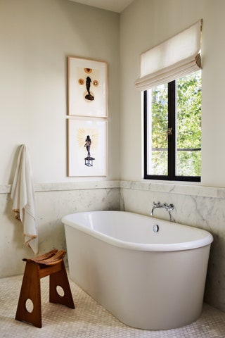Marble provides the backdrop for a Waterworks bathtub and the vintage Gilbert Marklund stool.